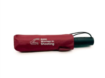 Folded BASC Women in Shooting umbrella in burgundy with white Women in Shooting branding and black handle on a white background.