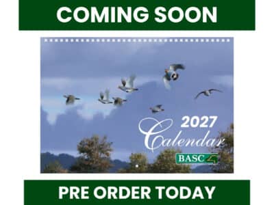 Promotional graphic for the BASC 2027 Calendar. The cover features a flock of grey partridge flying across a dramatic blue-grey sky above a tree-lined landscape, with the text "2027 Calendar" and the BASC logo. Bold green banners at the top and bottom read "COMING SOON" and "PRE ORDER TODAY".