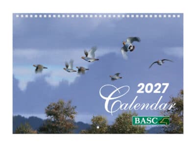 Cover of the BASC 2027 Calendar featuring a flock of partridges flying across a cloudy blue sky above a tree-lined landscape.
